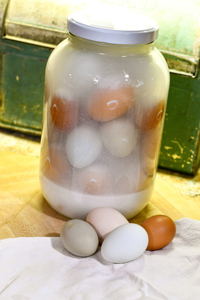 Eggs preserved in lime water sitting on a counter in a one gallon glass jar.